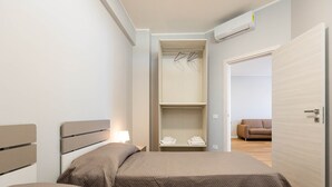 A hotel room with a bed, a wardrobe, and a seating area with a sofa. - Sea View Apartment (Margherita di Savoia)
