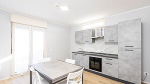 Una cucina moderna con mobili grigi, un piano di lavoro in marmo e un forno integrato.