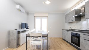 Una cucina moderna con zona pranzo, dotata di forno integrato, mobili grigi e un'ampia finestra.