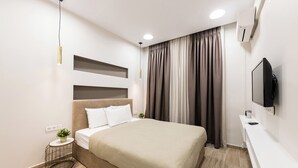 A modern bedroom with a bed, bedside table, and a mounted TV. - Portoseaview Modern Luxury Apartment 131 (Thessaloniki)