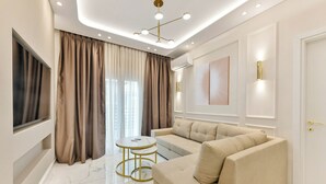 A modern living room with a beige sofa, a round coffee table, and a TV mounted on the wall. - Portoseaview Modern Luxury Apartment 131 (Thessaloniki)