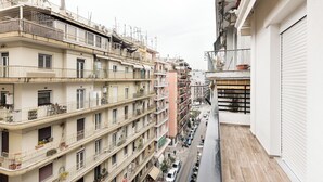 A multi-story residential building with balconies, a narrow street, and parked cars. - Portoseaview Modern Luxury Apartment 131 (Thessaloniki)
