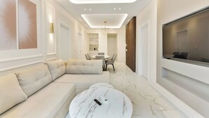 A modern living room with a sectional sofa, a marble coffee table, and a flat-screen TV mounted on the wall. - Portoseaview Modern Luxury Apartment 131 (Thessaloniki)