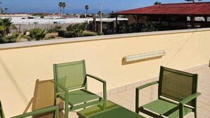 Ein Balkon mit grünen Stühlen und Blick auf das Meer und Gebäude.