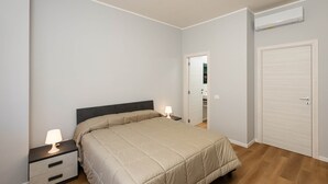 Ein Schlafzimmer mit Bett, Nachttischen, einem Kleiderschrank und einer Klimaanlage.
