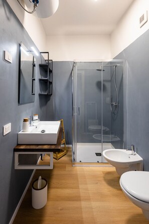 Un baño moderno con tocador de madera, cabina de ducha de vidrio y inodoro separado.