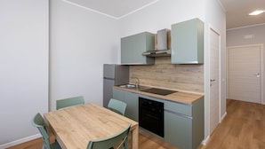 Una cucina compatta con un tavolo e sedie in legno, un forno integrato e mobili chiari.