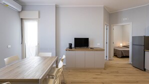 A modern kitchen with a dining area, a TV, and a refrigerator. - Sea View Apartment (Margherita di Savoia)