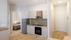 A compact kitchen with a refrigerator, stove, sink, and dishwasher. - Sea View Apartment (Margherita di Savoia)