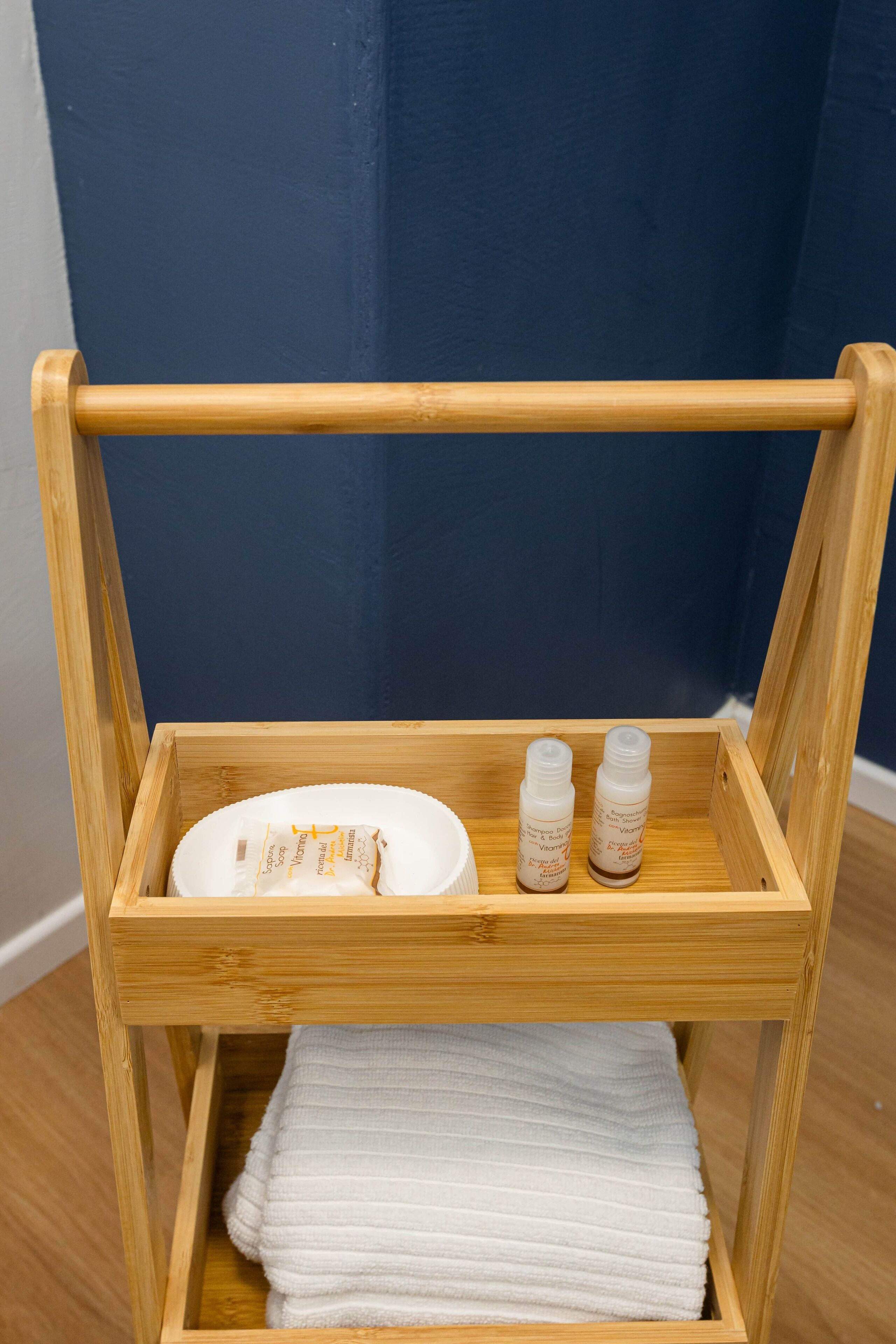 Una repisa de madera con una toalla blanca, dos botellas y un plato blanco.