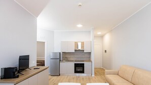 A modern kitchen with a built-in oven, a sink, and a refrigerator. There is a wooden dining table with two chairs. - Sea View Apartment (Margherita di Savoia)