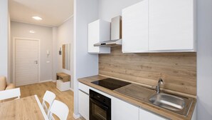 A modern kitchen with white cabinetry, a wooden countertop, and a stainless steel sink. - Sea View Apartment (Margherita di Savoia)