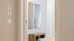A hallway with a wooden floor, a door with a number plate, and a vanity with a mirror and shelves. - Sea View Apartment (Margherita di Savoia)
