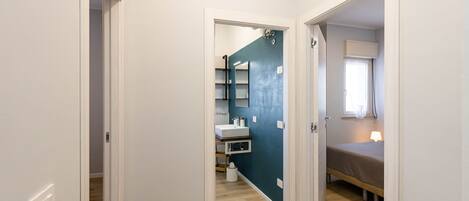 A narrow hallway with a bathroom on the left and a bedroom on the right.