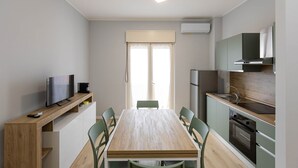 Eine moderne Küche mit Esstisch, Stühlen, Fernseher und eingebauten Geräten.
