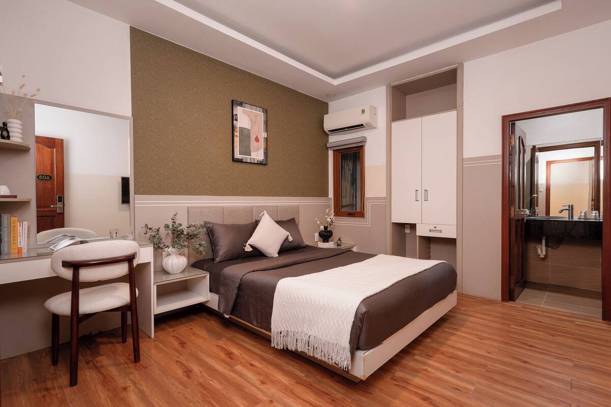 Un dormitorio moderno con cama, mesita de noche, silla y escritorio con su silla.