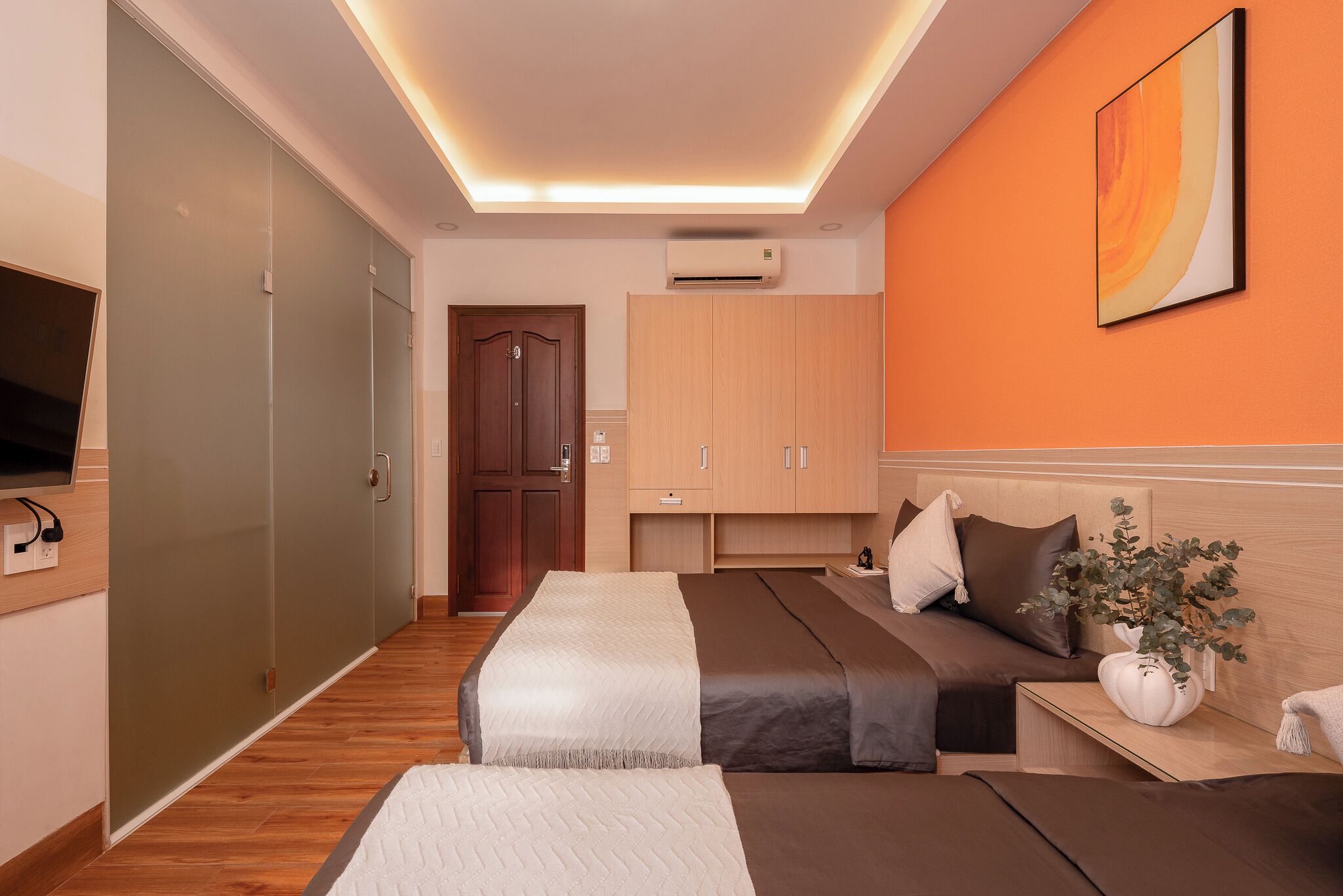 Une chambre d’hôtel moderne équipée d’un lit, de tables de chevet, d’une télévision et d’une armoire.