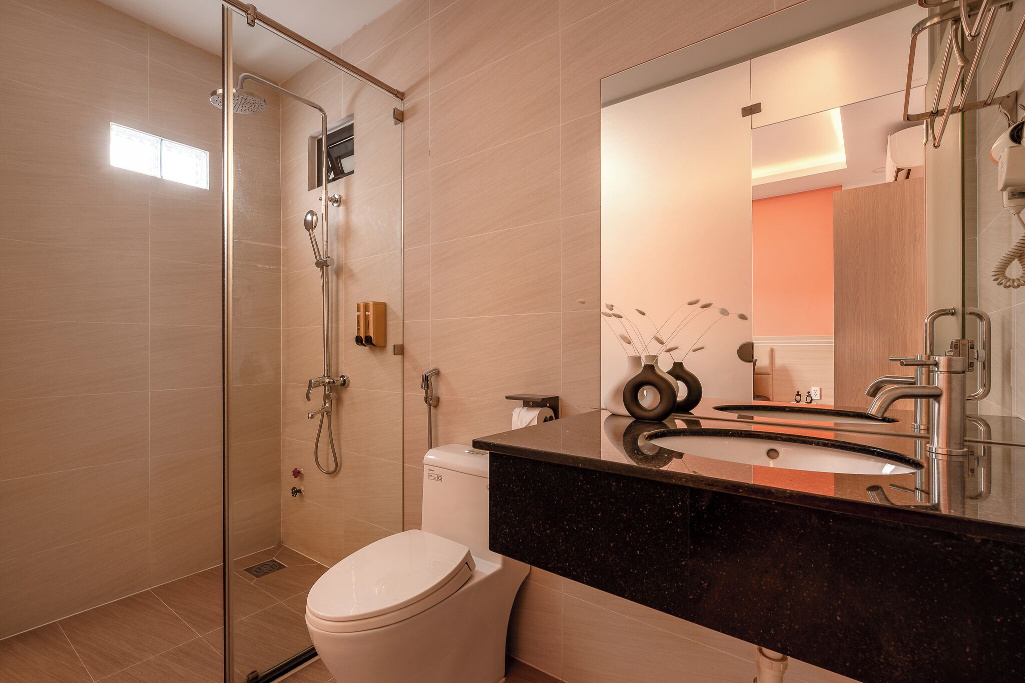 Ein modernes Badezimmer mit einer Duschkabine, einer weißen Toilette und einem schwarzen Granitwaschbecken mit großem Spiegel.