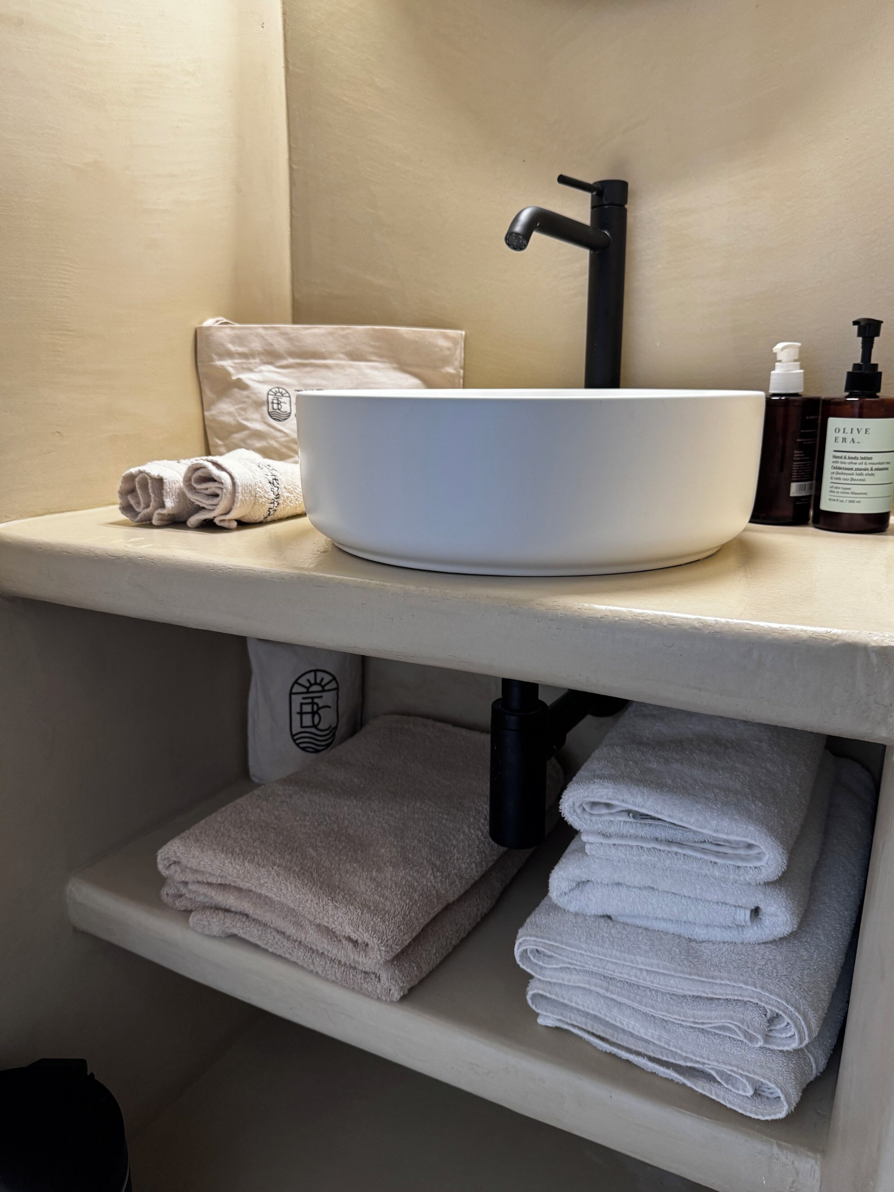 A bathroom with a white sink, towel rack, and shelves.