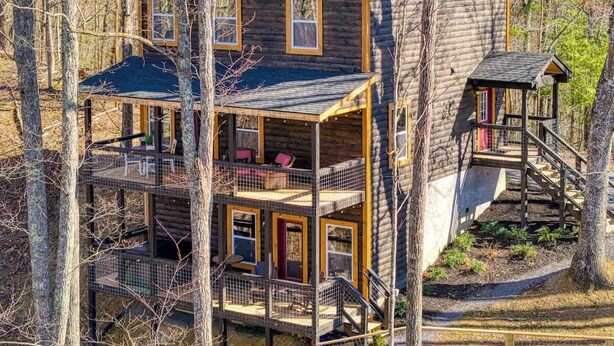 A multi-story log cabin with a balcony and a separate wooden structure attached to the main building. - Sassy Bear Hideaway by Beyond Expectations: 4BR w/ Firepit, Game Room & Hot Tub (Sevierville)
