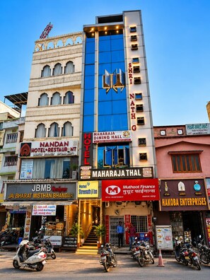 A hotel with multiple floors, a prominent sign for 'Maharaja Dining Hall,' and several other businesses on the ground floor.
