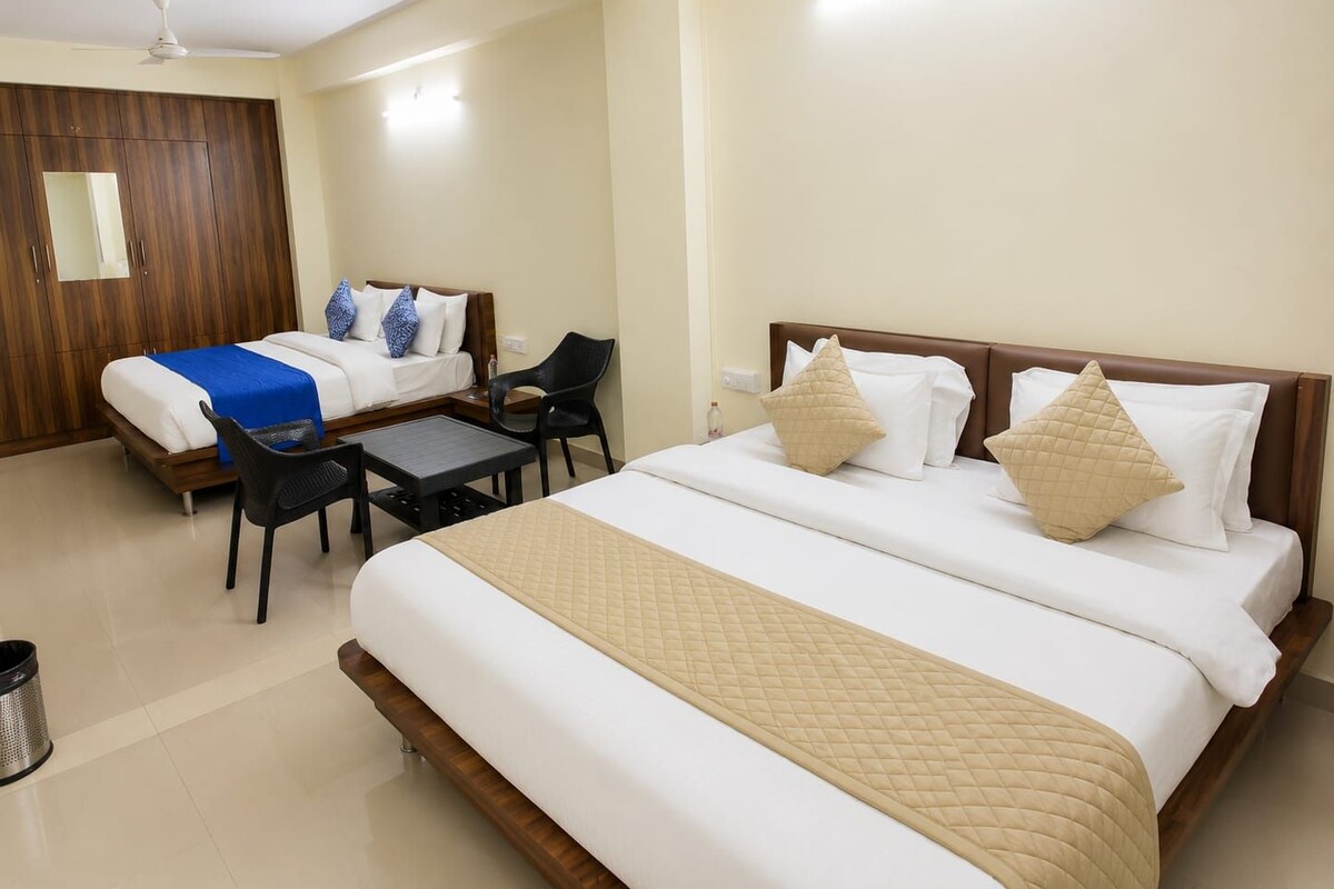 A hotel room with a large bed, a smaller bed, a desk, a chair, and a wardrobe.