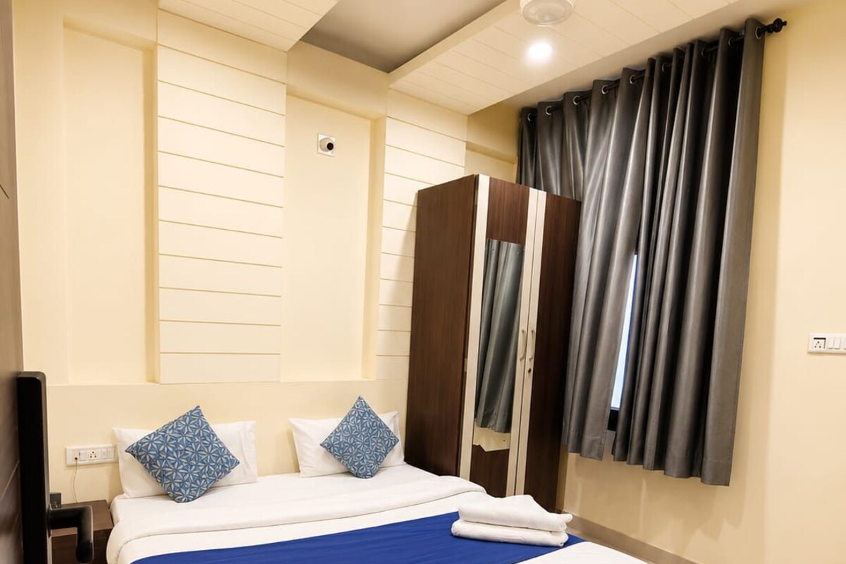 A hotel room with a large bed, a wardrobe, a ceiling fan, and a window with curtains.