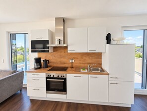 A modern kitchen with white cabinets, a built-in oven, a coffee maker, and a view of the outdoors. - Spacious Apartment with Exceptional Mountain View, Sauna and Terrace (Winterberg)