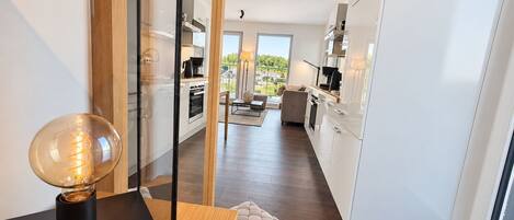 A modern kitchen with white cabinets, a wooden countertop, and a view of the outdoors.