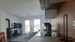 A modern kitchen with a built-in stove, a coffee machine, and a large window offering a view of the city. - Spacious Apartment with Exceptional Mountain View, Sauna and Terrace (Winterberg)