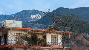 A building with a sign for Sowa Stays, featuring a balcony and a view of a mountainous landscape.