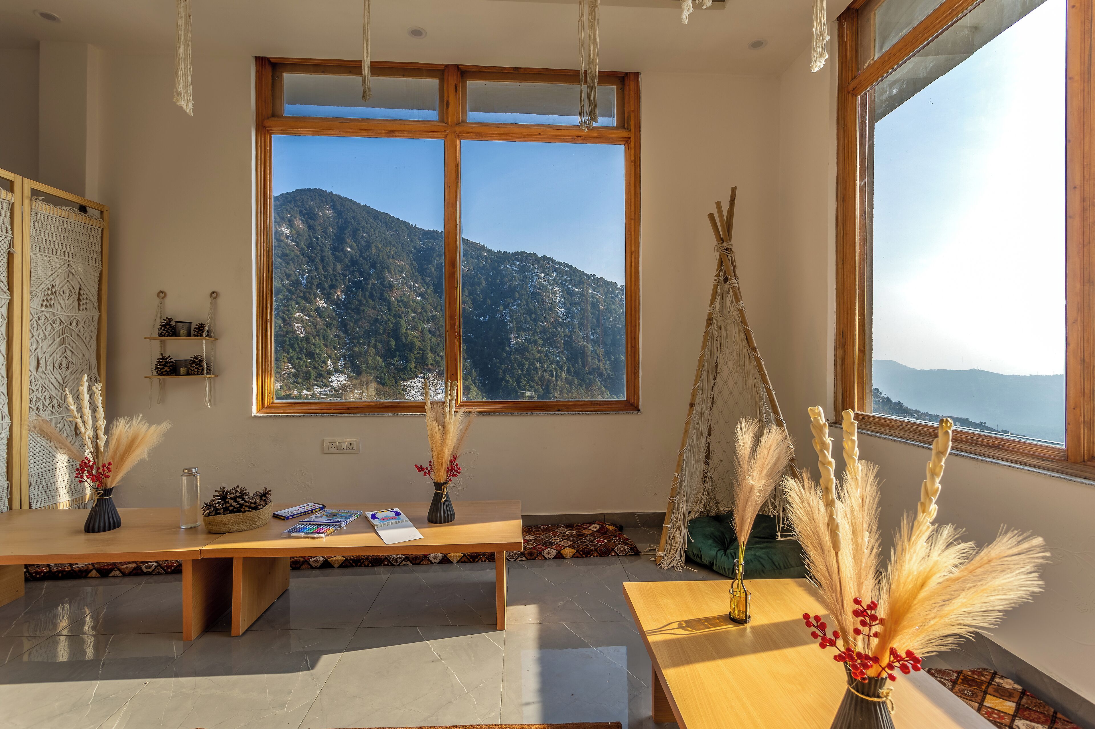 A room with a large window, a wooden table, and a view of a mountain.