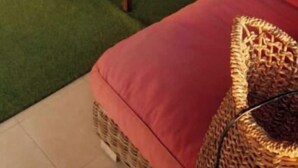A room with a red sofa, a small wooden table, and a wicker chair. - Aigle penthouse apartment (Saly)