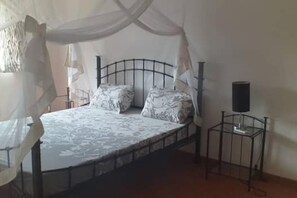 A bedroom with a bed, a bedside table, and a canopy. - Peaceful apartment in Saly, a stone's throw from the sea (Saly)