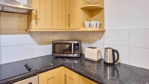 Eine Küche mit Holzausstattung, einer Mikrowelle, einem Toaster und einem Wasserkocher auf der Arbeitsfläche.