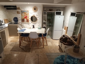 A compact kitchen with a dining area, a refrigerator, a microwave, and a small cabinet.