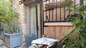 A rustic outdoor seating area with a table and chairs, a wooden door, and a sign with text. - Charming studio, suspended time, pets welcome (Malaucène)