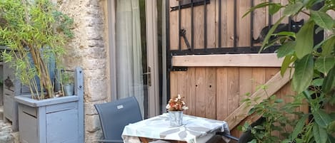 A rustic outdoor seating area with a table and chairs, a wooden door, and a sign with text.