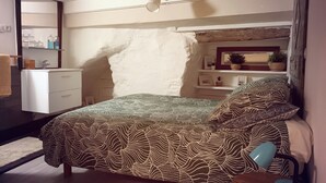 A bedroom with a bed, a nightstand, a dresser, a mirror, and a shelf with decorative items. - Charming studio, suspended time, pets welcome (Malaucène)