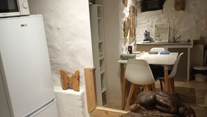 A compact kitchen with a white refrigerator, a microwave, a dining table with chairs, and a decorative sculpture on a cabinet. - Charming studio, suspended time, pets welcome (Malaucène)