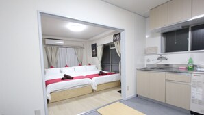 Een compacte hotelkamer met een bed, een kitchenette en een bankje.