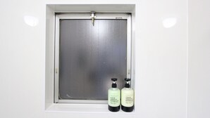 Een raam met een metalen hor en twee toiletartikelen op de vensterbank.