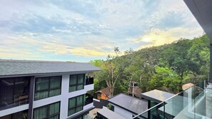 Un bâtiment moderne à étages, doté de grandes fenêtres et entouré d’une végétation luxuriante, dans un paysage vallonné.