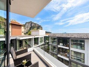 Een modern gebouw met grote ramen en een balkon met uitzicht op een bergachtig landschap.