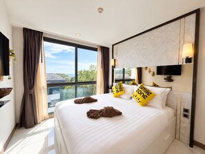 Une chambre d’hôtel dotée d’un grand lit, d’un téléviseur à écran plat, d’une tête de lit en marbre et offrant une vue sur l’extérieur.
