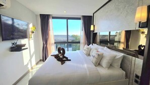 Hotelkamer met een groot bed, een flatscreen televisie, een raam met gordijnen en een wandlamp.