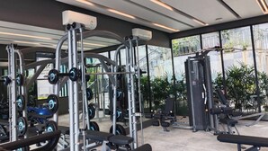 Een moderne fitnessruimte met diverse trainingsapparaten, grote ramen en een schoon, goed verlicht interieur.
