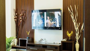 Een moderne woonkamer met een flatscreen televisie aan de muur, een glazen salontafel en een bank.
