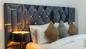 Een moderne slaapkamer met een gebobbelde hoofdbord, een nachtkastje met lades en een lamp.