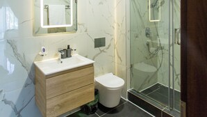 Een moderne badkamer met een marmeren wand, een houten wastafelmeubel, een douchecabine met glazen wanden en een roze vloerkleed.